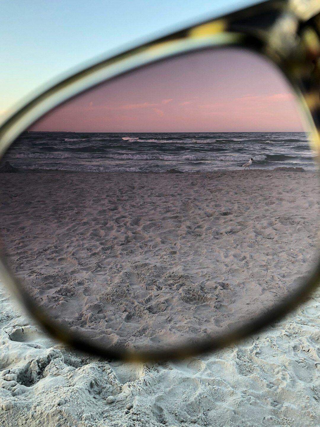 Polarized luxury sunglasses resting on beach sand near the ocean